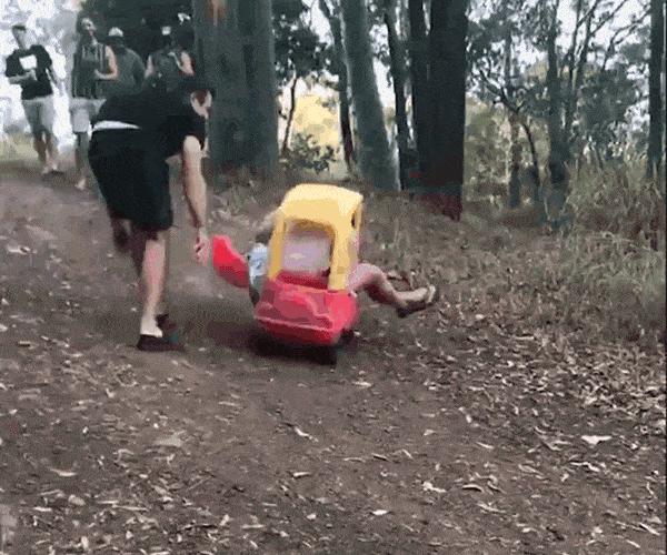 boy with small truck rolls down a slope in the forest